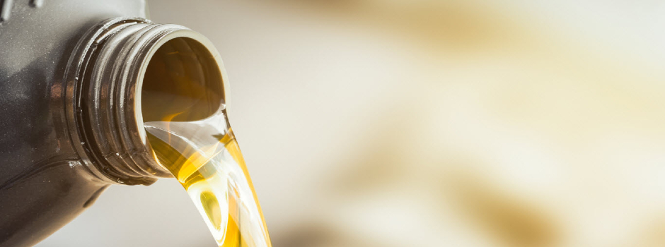 grey bottle containing engine oil being poured into engine